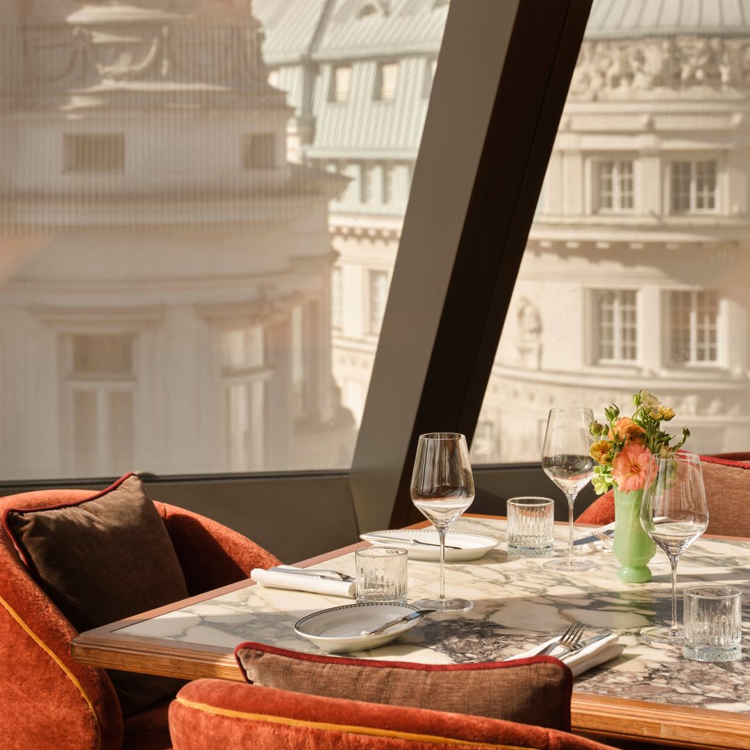 A table decorated with Flowers and a beautiful window view at Viennas old town buildings at Neue Hoheit Restaurant 